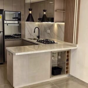 Modern custom-designed luxury kitchen in Dubai featuring matte dark grey cabinetry, warm wooden breakfast bar, pendant lighting, integrated shelving, and minimalist contemporary interior design.