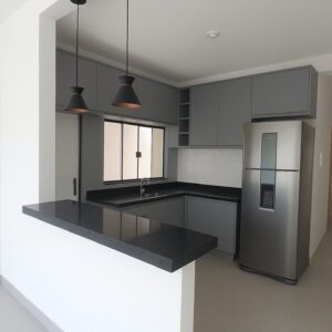 Modern custom-designed luxury kitchen in Dubai featuring matte dark grey cabinetry, warm wooden breakfast bar, pendant lighting, integrated shelving, and minimalist contemporary interior design.