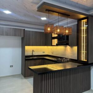 Modern custom-designed luxury kitchen in Dubai featuring matte dark grey cabinetry, warm wooden breakfast bar, pendant lighting, integrated shelving, and minimalist contemporary interior design.
