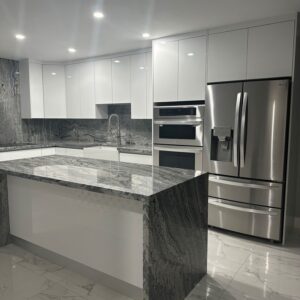 Modern custom-designed luxury kitchen in Dubai featuring matte dark grey cabinetry, warm wooden breakfast bar, pendant lighting, integrated shelving, and minimalist contemporary interior design. Modern custom-designed luxury kitchen in Dubai featuring matte dark grey cabinetry, warm wooden breakfast bar, pendant lighting, integrated shelving, and minimalist contemporary interior design.