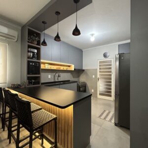 Modern custom-designed luxury kitchen in Dubai featuring matte dark grey cabinetry, warm wooden breakfast bar, pendant lighting, integrated shelving, and minimalist contemporary interior design. Modern custom-designed luxury kitchen in Dubai featuring matte dark grey cabinetry, warm wooden breakfast bar, pendant lighting, integrated shelving, and minimalist contemporary interior design.